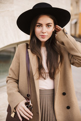 Portrait of brunette young fashion woman in autumn coat walking outdoors