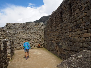 Obraz na płótnie Canvas A woman tourist walking in the ancient Inca town of Machu Picchu, Ruins of Inca Empire city, Peru