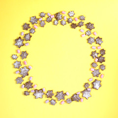 Concept Christmas round frame lined with snowflakes gingerbread cookies sprinkled with icing sugar on a yellow background.