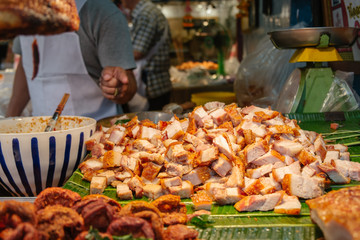 Chopped crispy pork on banana leaves for sale in a local street food shop in Bangkok, Thailand.