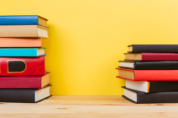 Simple composition of many hardback books, raw of books on wooden table and pastel yellow background