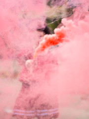 Pink smoke grenade. Smoking bomb in the hands of a vandal. Riots concept vertical shot
