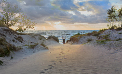 guy with his hands up on the shore of a stormy sea