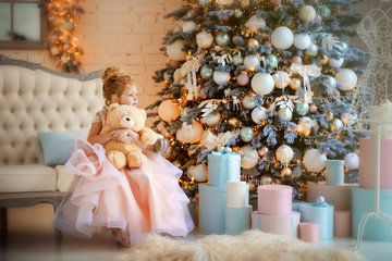 Fototapeta na wymiar 5 years old girl in beautiful light pink dress with creamy teddy bear in christmas time