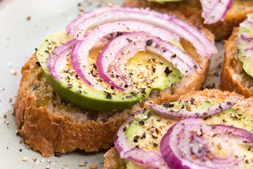 Sandwich with fresh avocado and onion on a plate