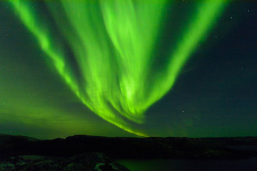 Aurora borealis over the hills. At night in the sky in the north.