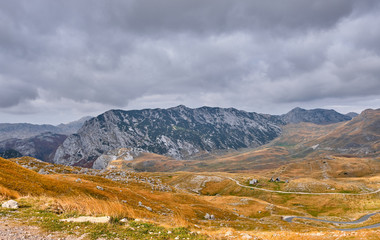 Fototapeta na wymiar Rocky mountains covered with autumn meadow against the background of a stormy sky