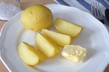 Cooked potatoes with butter and salt as dinner or lunch on white plate. Cose-up