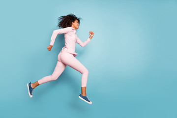 Fototapeta na wymiar Full body photo of amazing dark skin wavy lady jumping high speed race competition participant run to finish line wear pink shirt trousers isolated blue color background