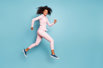 Fototapeta na wymiar Full length photo of amazing dark skin wavy lady jumping high speed race competition participant wear pink shirt trousers isolated blue color background