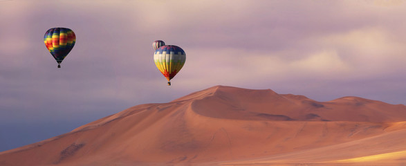 Obraz premium Three colorful hot air balloons over the sand dunes in Namib Desert. Artistic picture. Beauty world.