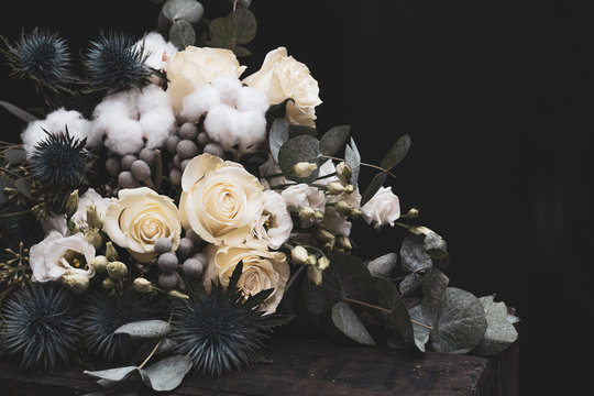 Winter wedding bouquet of white roses, cotton and eringium on a black background. The bride's bouquet.