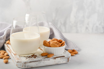 Almond milk and almonds on a white wooden cutting board.