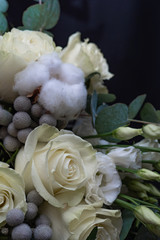 Winter wedding bouquet of white roses, cotton and eringium on a black background. The bride's bouquet.