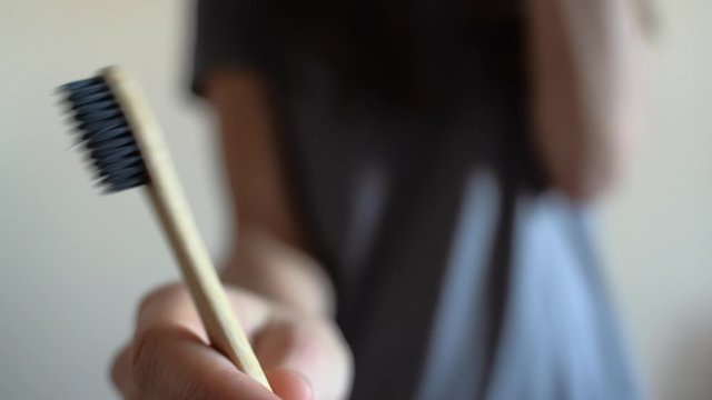 Closeup at woman hand is showing Bamboo toothbrush.Zero waste, bathroom, plastic free
