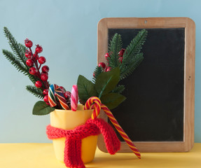 Christmas candy canes in yellow mug with berries holly branches and Christmas decoratio