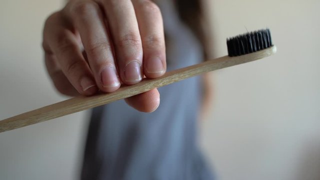 Closeup at woman hand is showing Bamboo toothbrush.Zero waste, bathroom, plastic free