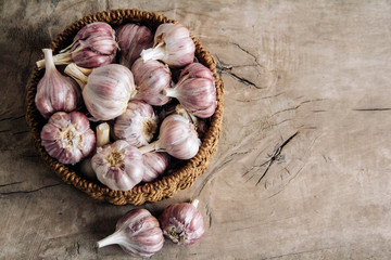 Garlic in a wicker basket on a wooden table background. Top view. Copy, empty space for text