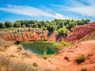 Fototapeta na wymiar The lake in a old bauxite's red soils quarry cave in Apulia, Otranto, Salento, Italy. The digging was filled with natural waters.