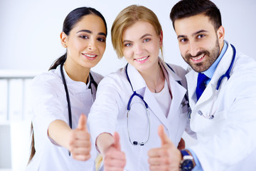 Fototapeta premium Arab and european smiling doctors shows thumb up. Healthcare concept