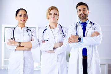 Fototapeta premium Mixed races team of medical doctors are looking at camera and smiling while standing in hospital
