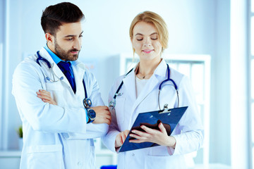 Two doctors holding a folder and talking about patient