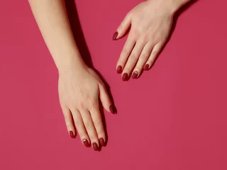  Manicure in a trandy dark red color on a red background. Flat lay style. © Natalia Sarkar