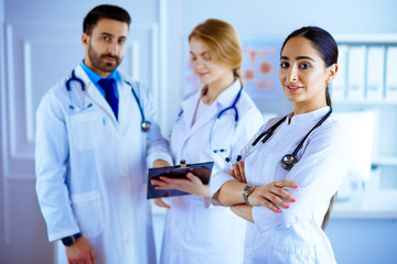 Fototapeta premium Attractive female arab doctor smiling in front of medical stuff in hospital