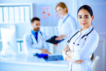 Confident female doctor in front of team, looking at camera smiling, multiracial team with arab female doctor