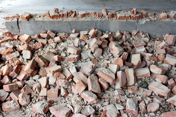 Pile of construction material and broken destroyed red bricks mixed with concrete at abandoned...