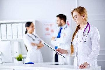 Female Doctor standing and reading diagnosis in Front of her team in the hospital