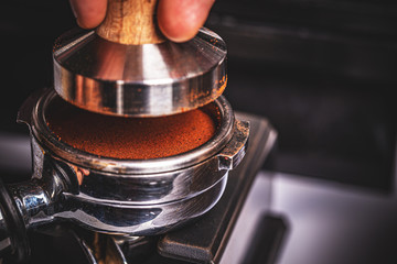 Barista pressing ground coffee