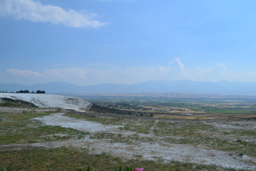 Pamukkale travertines captured with fields and some people around. Captured in daytime.