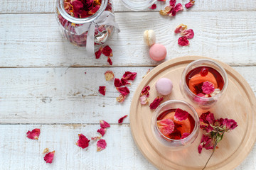 Two cups of dried rose petals tea on a white wooden table. Morning tea for two