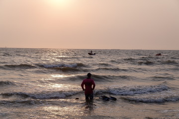 man walking on the beach at sunset.