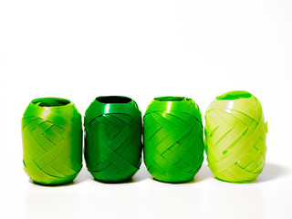 four rolls of ribbon for decorating gifts in different green colours in front of  a white background