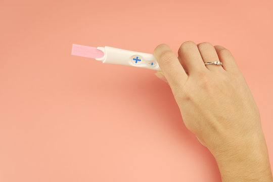 A married young woman holding a pregnancy test with a positive result. Copy space.
