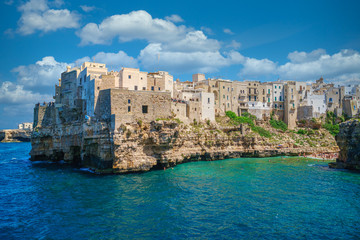 Fototapeta na wymiar Houses on a rocky seashore in the popular tourist town of Polignano a Mare, sunny summer day
