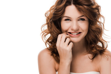 Fototapeta premium cheerful curly girl smiling and touching face isolated on white