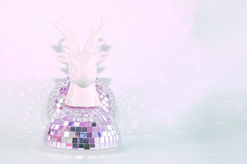 A sculpture of a deer head standing on a disco ball on a pink mint background. Concept abstraction, party.
