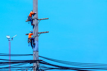 Electricians are climbing on electric poles to install and repair power lines.