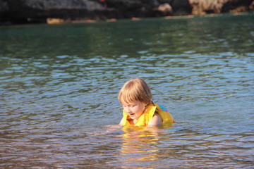 a child in a vest bathes in the sea