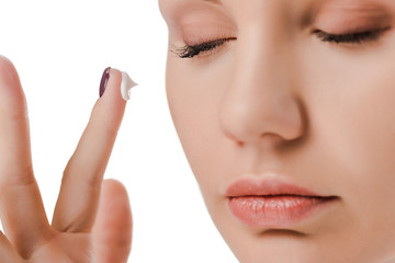 Obraz na płótnie Canvas close up of woman with closed eyes and face cream on finger isolated on white