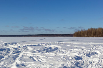 Beautiful winter landscape with field of white snow and forest on horizon on sunny frosty day.