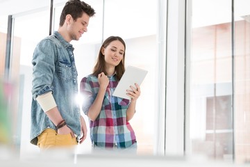 Businesswoman showing plans through digital tablet to colleague in office