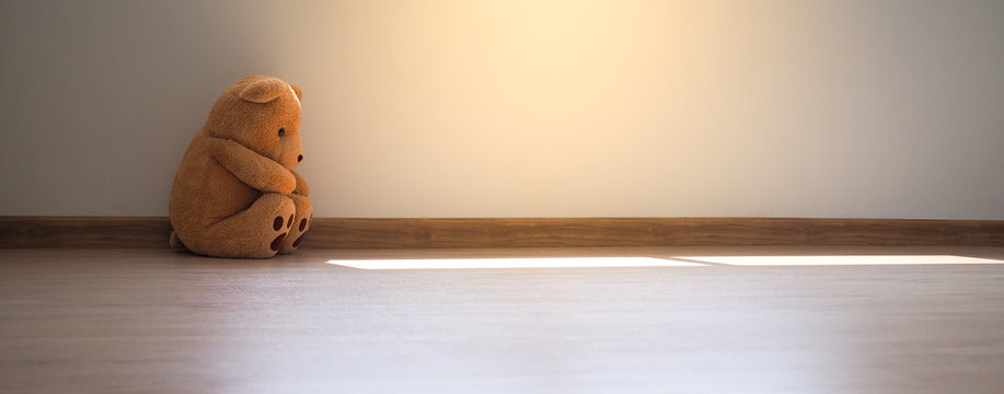 Naklejki Child concept of sorrow. Teddy bear sitting leaning against the wall of the house alone, look sad and disappointed.            