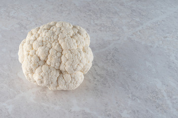 Fototapeta na wymiar A large, fresh head of cauliflower on a light marble background. The concept of the diet.