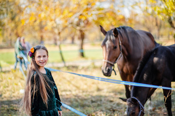 Obraz premium Happy girl stroking a horse, standing near the fence in the stable.