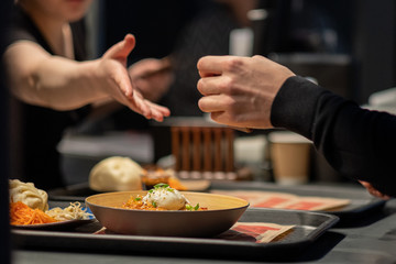 Hands reaching out to each other in the dark over a plate of food. A restaurant.