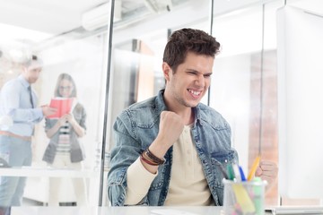 Businessman celebrating success while sitting in office